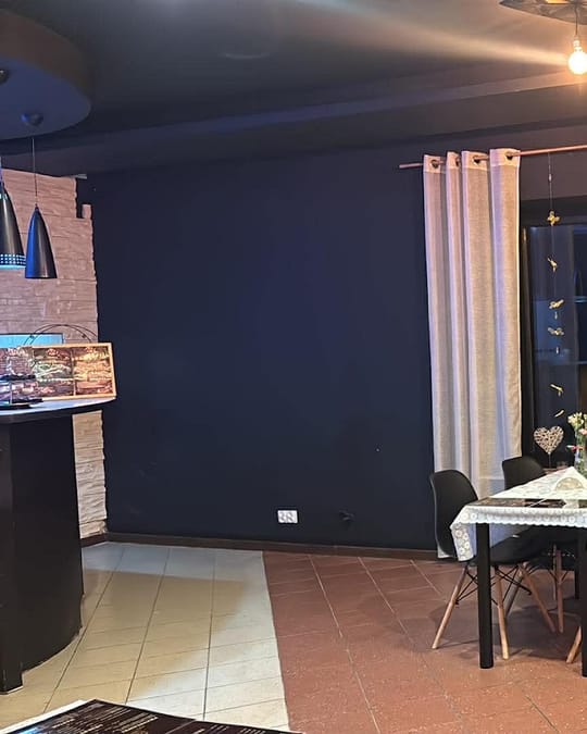 Wnętrze bistro wieczorem: stoliki z koronkowymi obrusami i ciepłe światło żarówek